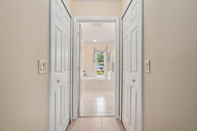 hallway with light tile patterned floors and a textured wall