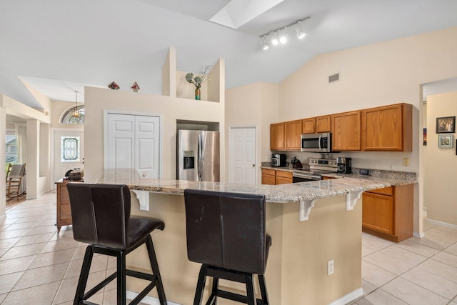 kitchen featuring visible vents, light tile patterned flooring, rail lighting, brown cabinets, and stainless steel appliances