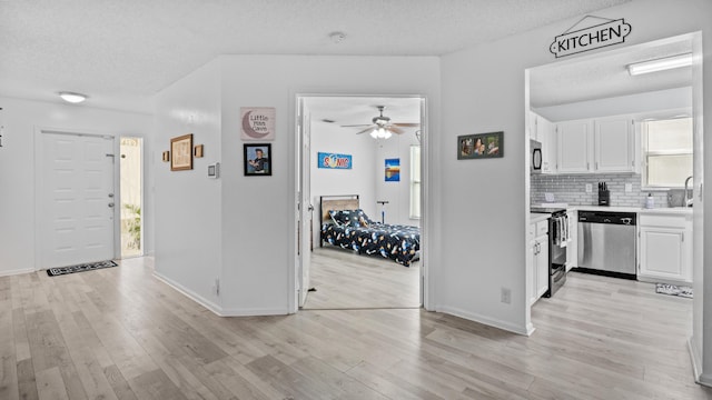 interior space with a textured ceiling, a healthy amount of sunlight, and light wood-style flooring