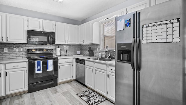 kitchen with backsplash, light wood-type flooring, a sink, light countertops, and black appliances