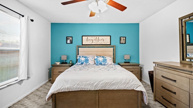bedroom featuring baseboards, light carpet, a ceiling fan, and a textured ceiling