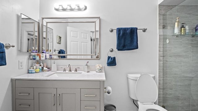 bathroom featuring toilet, tiled shower, and vanity