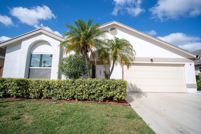 view of front of house with a garage, stucco siding, driveway, and a front yard