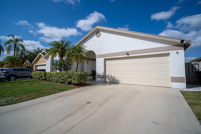 ranch-style house featuring concrete driveway, an attached garage, a front yard, and stucco siding