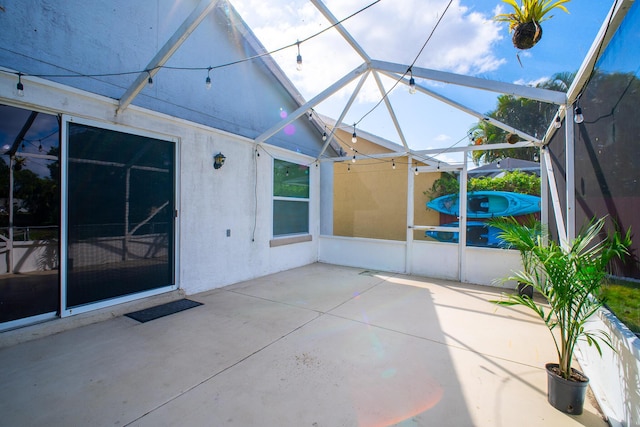 view of patio featuring glass enclosure and a jacuzzi