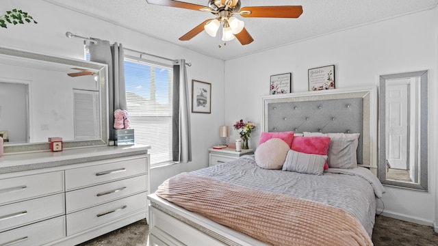 bedroom featuring a textured ceiling, ceiling fan, multiple windows, and dark colored carpet