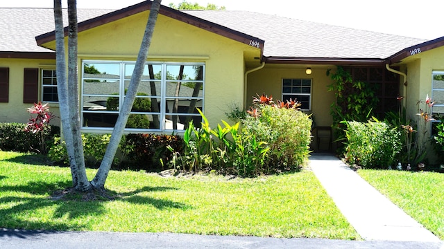 view of side of home featuring a lawn, stucco siding, and a shingled roof
