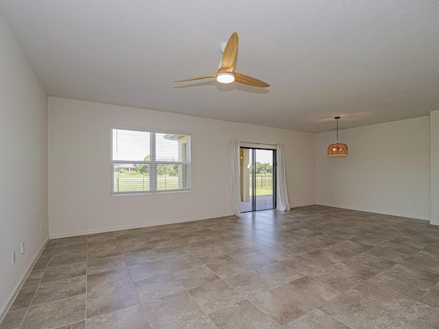 empty room featuring stone finish flooring, a ceiling fan, and baseboards