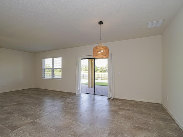 spare room with baseboards, visible vents, and a textured ceiling