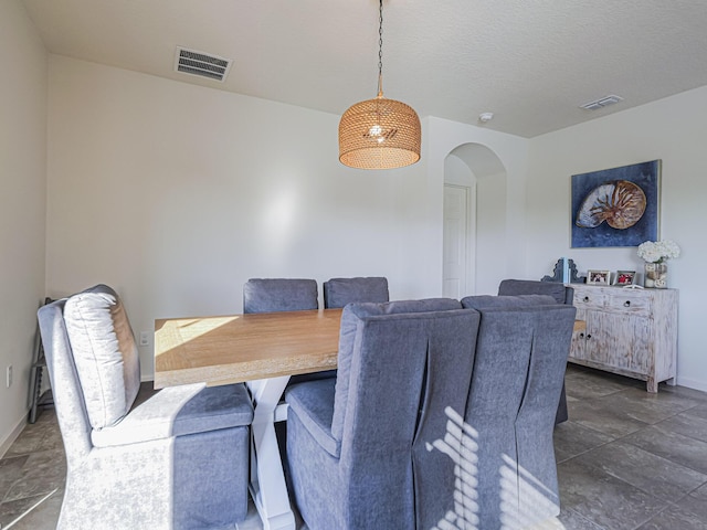 dining area with baseboards, visible vents, and arched walkways