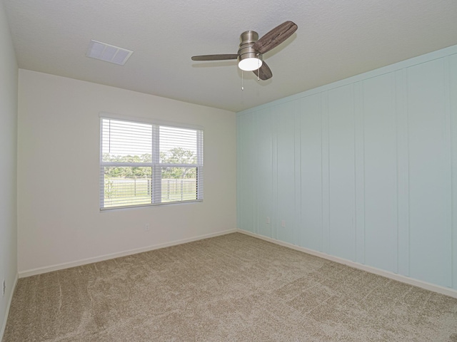 empty room with baseboards, visible vents, ceiling fan, and light colored carpet