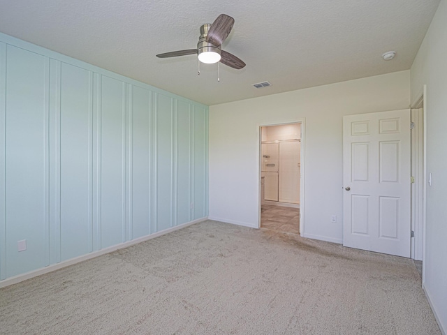 unfurnished bedroom with ceiling fan, visible vents, carpet, baseboards, and a textured ceiling