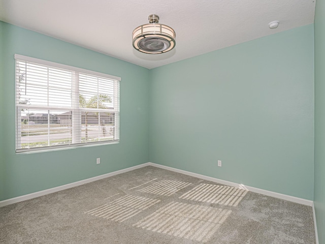 carpeted spare room featuring baseboards