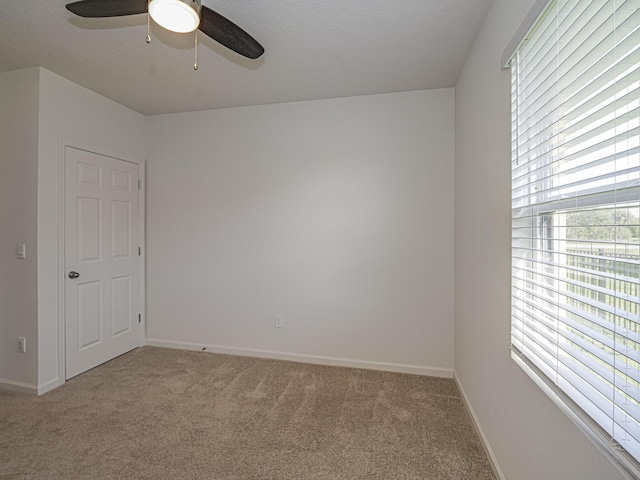 empty room with light colored carpet, plenty of natural light, and a ceiling fan