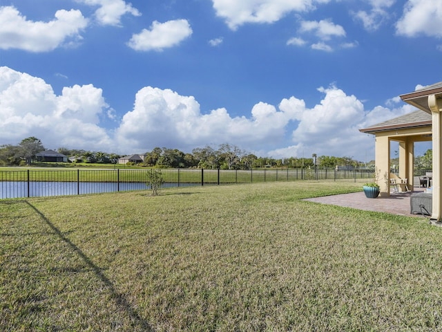view of yard with a patio, a water view, and a fenced backyard