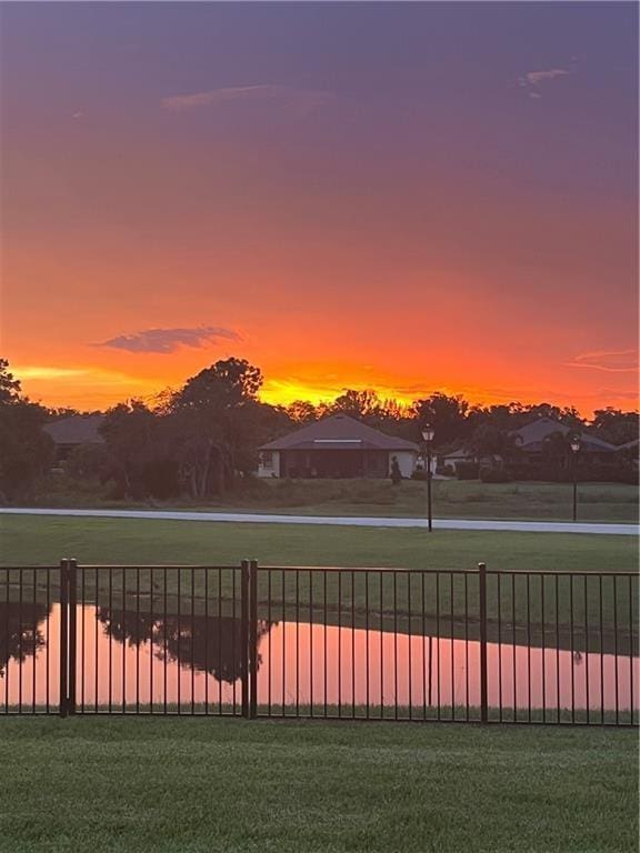 yard at dusk featuring fence and a water view
