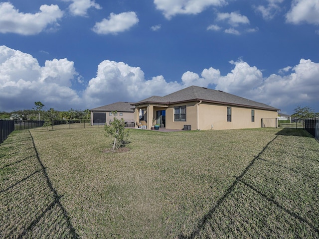 rear view of house with stucco siding, a yard, a patio, and a fenced backyard
