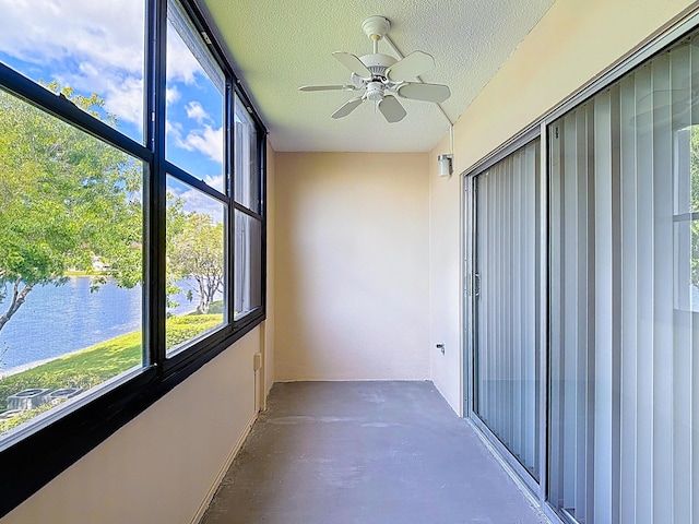 unfurnished sunroom with a ceiling fan and a water view