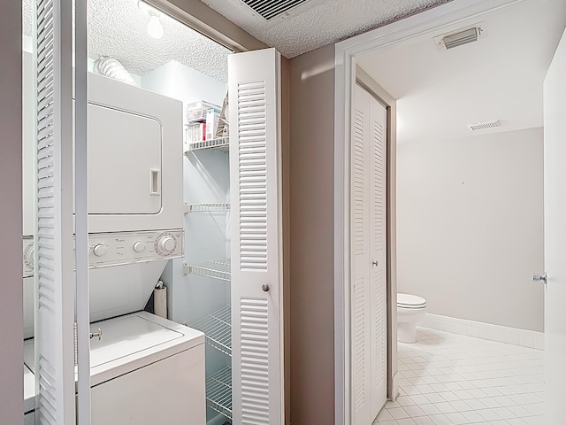 laundry room with stacked washer and dryer, tile patterned floors, visible vents, and laundry area
