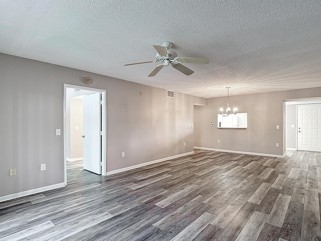 unfurnished room with wood finished floors, ceiling fan with notable chandelier, baseboards, visible vents, and a textured ceiling