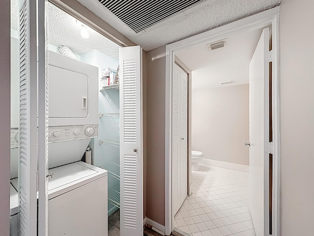 washroom with stacked washer / dryer, tile patterned floors, visible vents, and laundry area