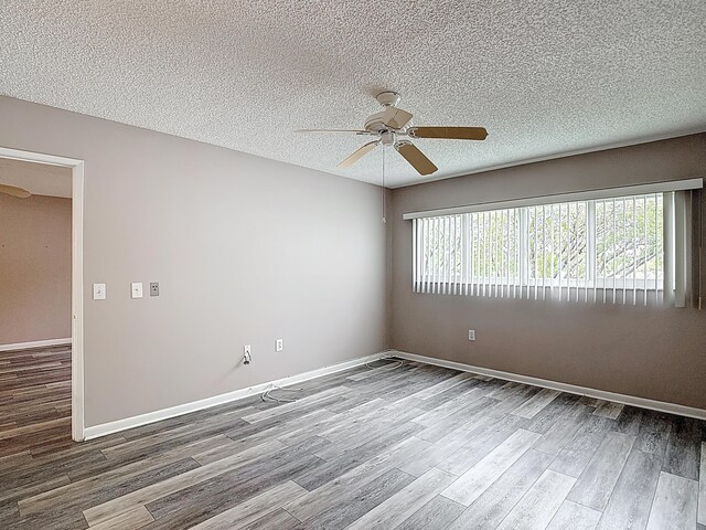 unfurnished room with baseboards, wood finished floors, ceiling fan, and a textured ceiling
