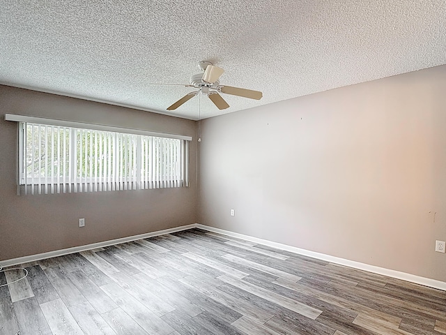 unfurnished room featuring a textured ceiling, ceiling fan, a wealth of natural light, and wood finished floors