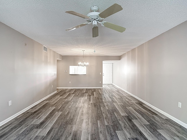 unfurnished dining area with ceiling fan with notable chandelier, baseboards, visible vents, a textured ceiling, and dark wood-type flooring