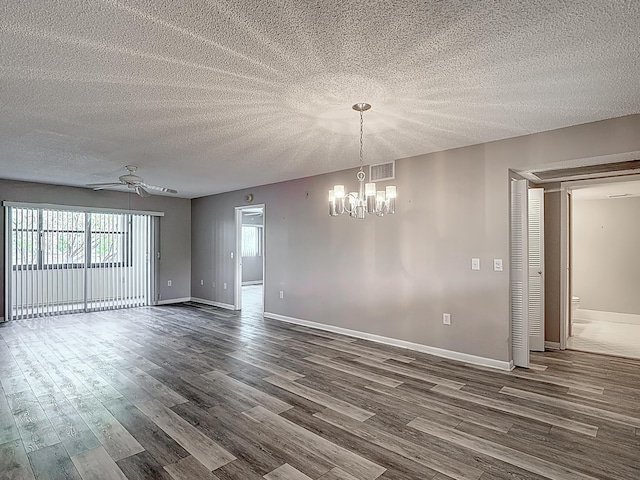 unfurnished room featuring a textured ceiling, visible vents, baseboards, dark wood-type flooring, and ceiling fan with notable chandelier