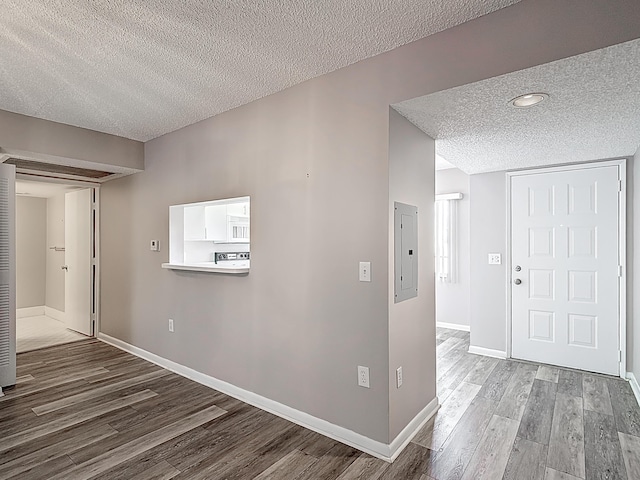 entryway with a textured ceiling, wood finished floors, and baseboards