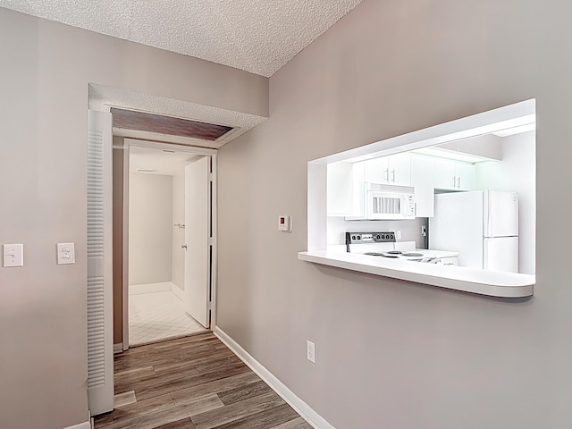 hall with a textured ceiling, baseboards, and dark wood finished floors