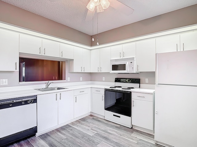 kitchen featuring white appliances, light wood-style flooring, light countertops, a sink, and white cabinetry