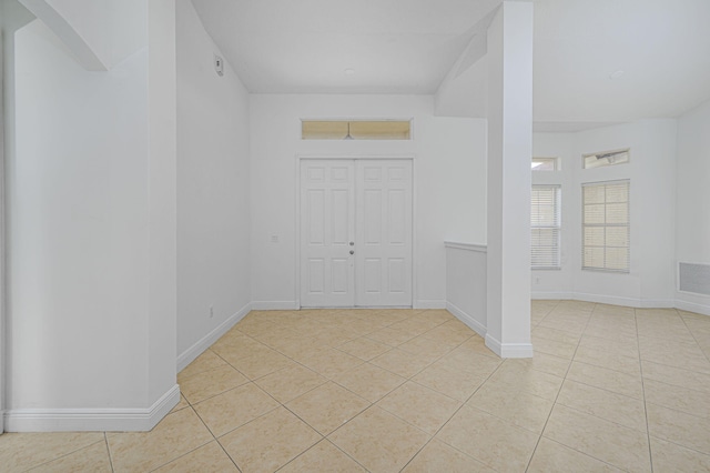 empty room featuring baseboards, visible vents, and light tile patterned floors
