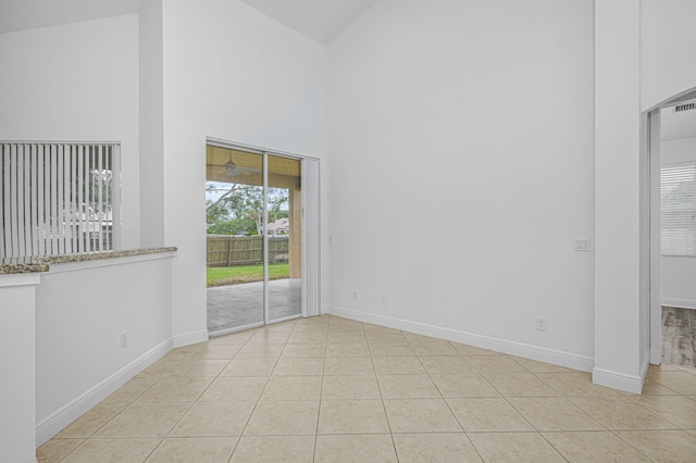 unfurnished room with light tile patterned flooring, high vaulted ceiling, and baseboards