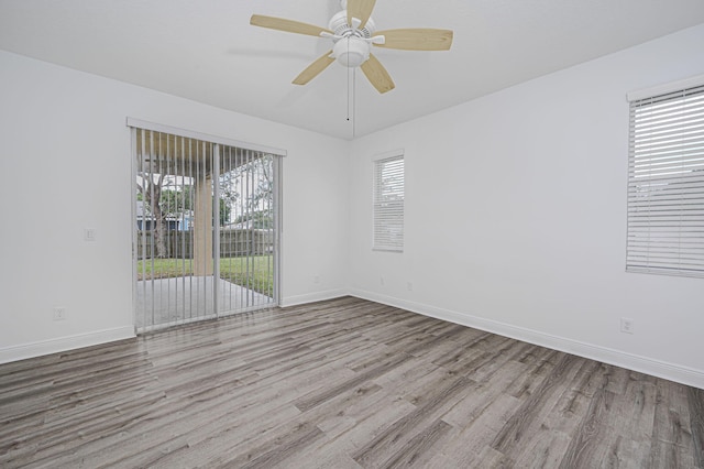 spare room with baseboards, wood finished floors, a wealth of natural light, and ceiling fan