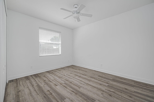 empty room with ceiling fan, wood finished floors, and baseboards