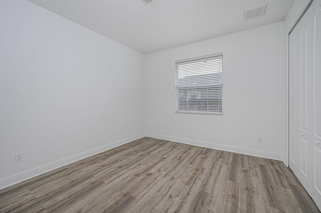 spare room with visible vents, wood finished floors, and baseboards