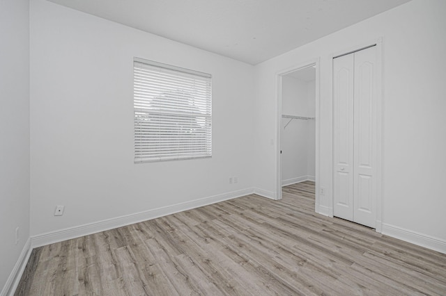 unfurnished bedroom with baseboards, wood finished floors, and a closet
