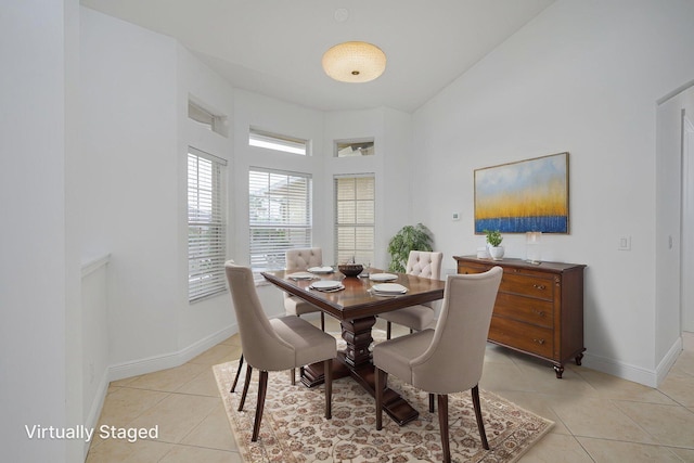 dining room with baseboards, light tile patterned flooring, and a towering ceiling