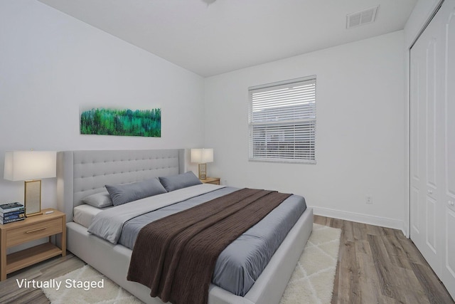 bedroom featuring lofted ceiling, visible vents, baseboards, a closet, and wood finished floors