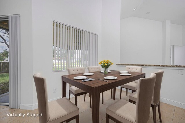 dining space featuring light tile patterned flooring, high vaulted ceiling, and baseboards