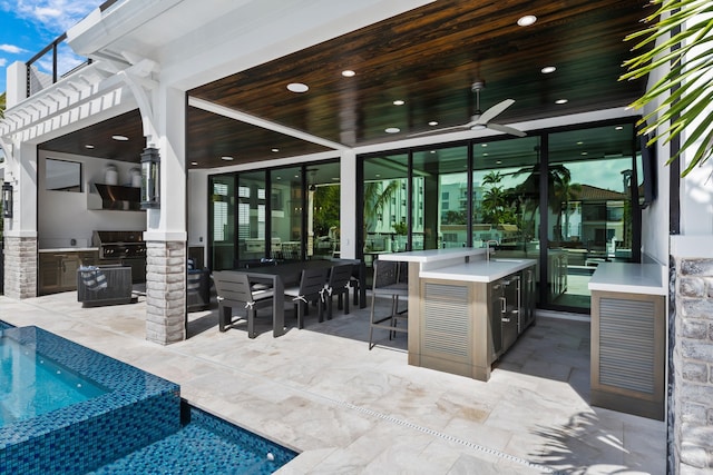 view of patio with a sink, a pool with connected hot tub, a grill, exterior kitchen, and a ceiling fan
