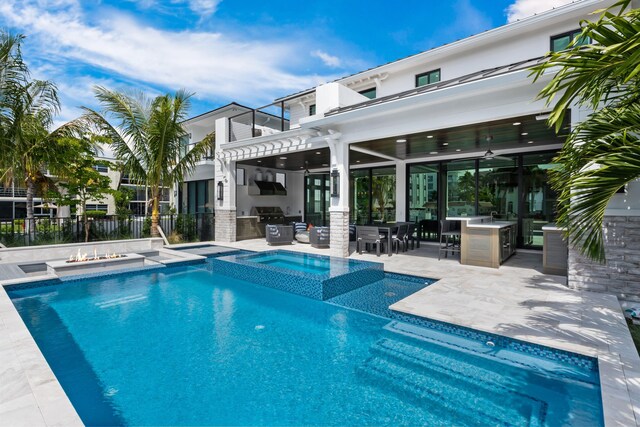view of swimming pool featuring exterior kitchen, a patio area, outdoor dining area, ceiling fan, and a pool with connected hot tub