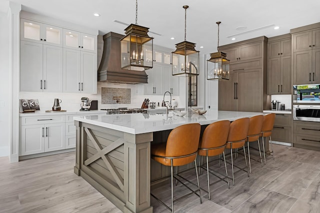 kitchen featuring a large island, light wood-type flooring, decorative backsplash, and custom range hood