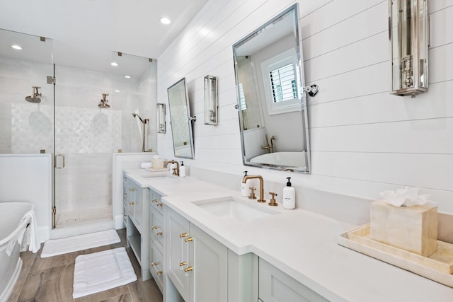 full bathroom featuring a soaking tub, wood finished floors, a shower stall, and a sink