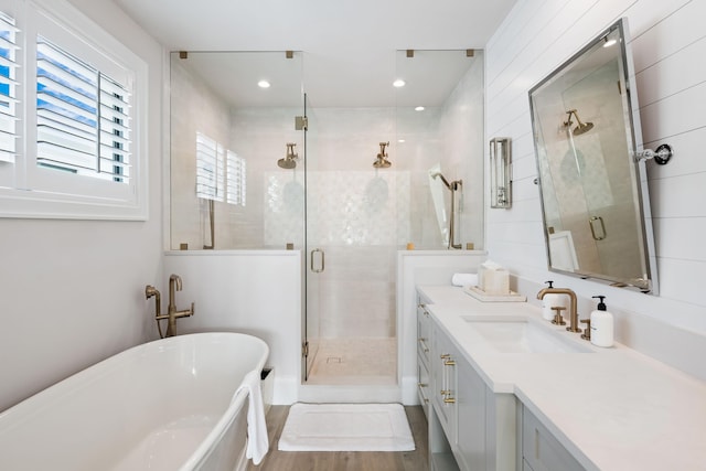 bathroom with a freestanding tub, a stall shower, wood finished floors, and vanity