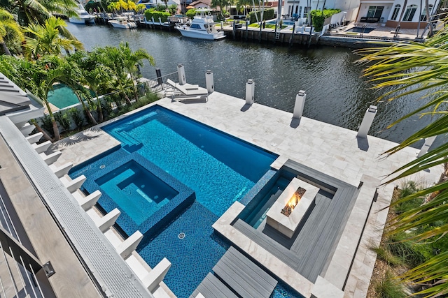 view of swimming pool with a pool with connected hot tub, a fire pit, and a water view