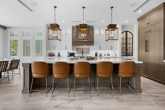 kitchen featuring backsplash, custom exhaust hood, a large island, and light countertops