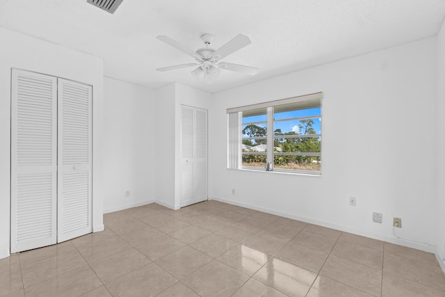 13648 Coconut Palm Ct Unit B, Delray Beach, FL 33484 - unfurnished bedroom with light tile patterned floors, visible vents, ceiling fan, baseboards, and two closets