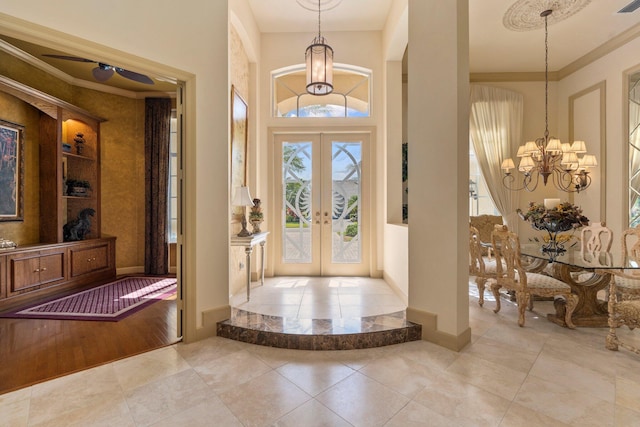 foyer with an inviting chandelier, tile patterned floors, ornamental molding, and french doors